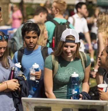 Students hold reusable water bottles at campus event